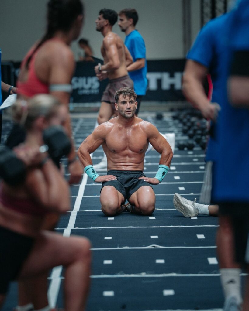 Atleta de rodillas recuperando el aliento en la pista de competición