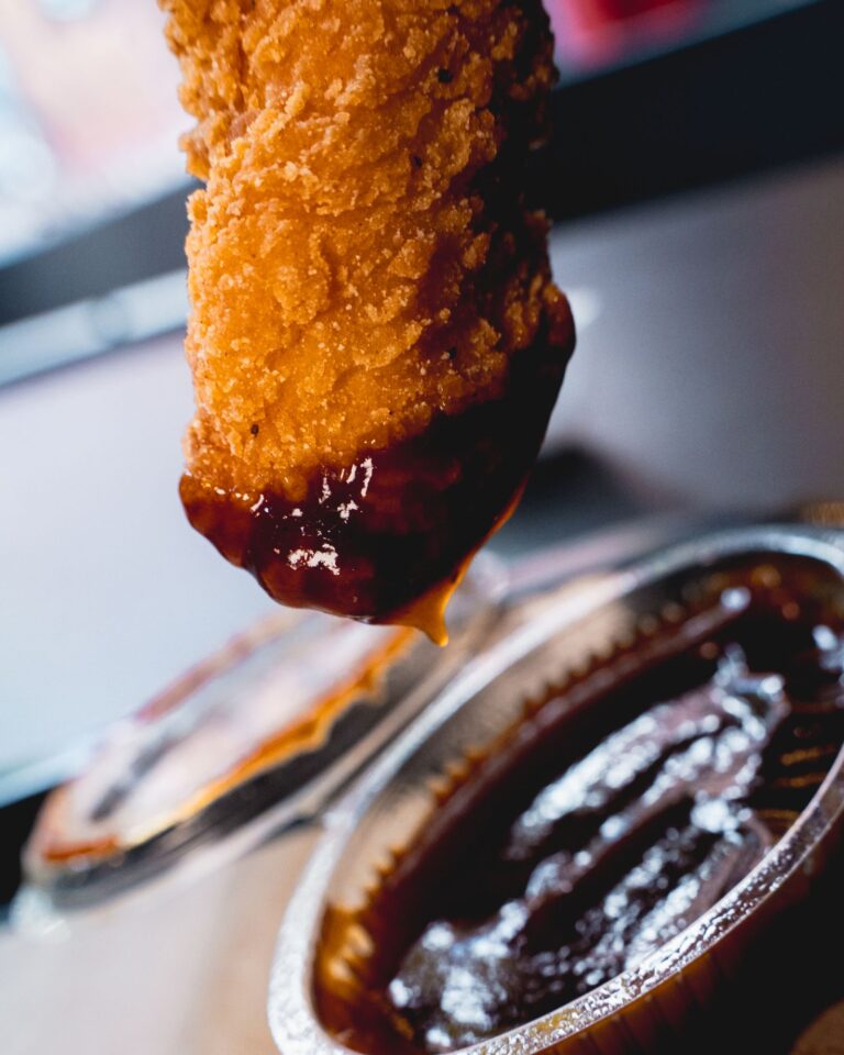 Tira de pollo crujiente mojada en salsa barbacoa, fotografía de producto para hostelería